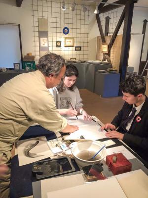 バルビゾン村から来られた学生に書道を教える様子の画像